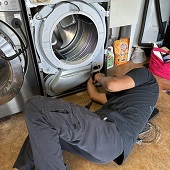 мастер из сервисного центра Whirlpool чистит сливной насос в стиральной машине